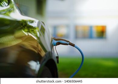 Electric Car Is Charging In Front Of House