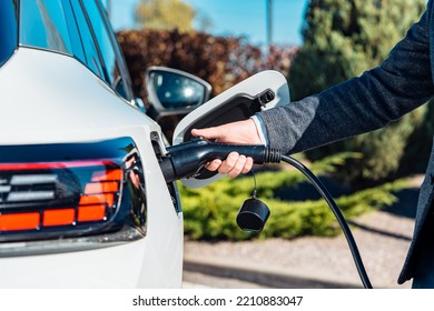 Electric car charging. Man's hand inserting the electrical connector to the electric car. Green energy, eco friendly fuel.