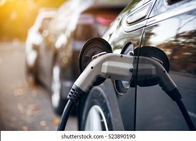 Electric car charging on parking lot with electric car charging station on city street. Electric cars in the row ready for charge. Close up of power supply plugged into an electric car being charged.
 - Shutterstock ID 523890190