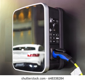Electric car charging on parking lot with electric car charging station on city street. Close up of power supply plugged into an electric car being charged.