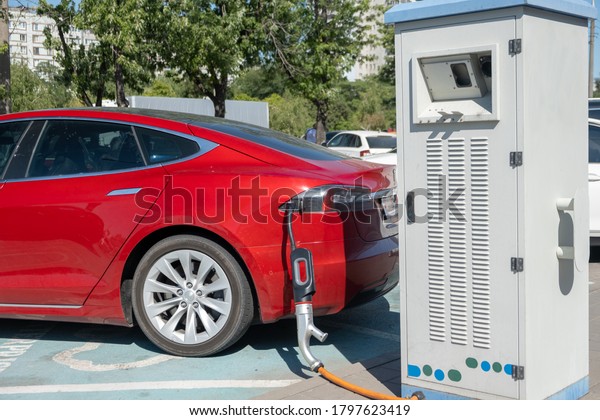 Electric car charging on parking lot with\
electric car charging station on city street. Electric cars in the\
row ready for charge. Close up of power supply plugged into an\
electric car being\
charged.\
