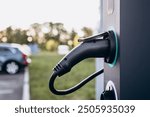 Electric car charging at plug in charging station in a public car park. Renewable clean energy car for progressive eco awareness lifestyle concept.