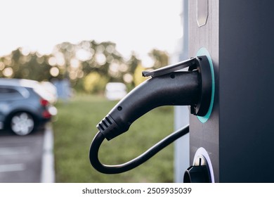 Electric car charging at plug in charging station in a public car park. Renewable clean energy car for progressive eco awareness lifestyle concept.