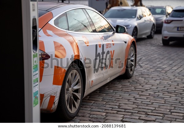 Electric car\
charging point with Tesla car plugged in decorated with Bitcoin and\
Nasdaq logotypes. Bitcoin and cryptocurrency market advertising on\
Tesla car. Sweden, Stockholm\
2021.11.30