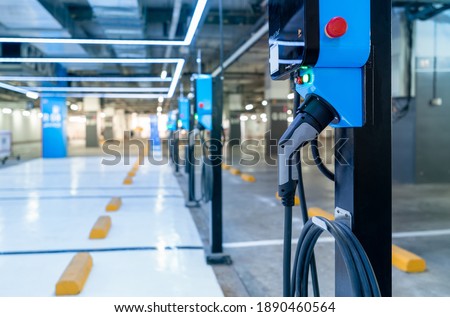 Electric car charging station for charge EV battery. Plug for vehicle with electric engine. EV charger. Clean energy. Charging point at car parking lot. Green power. Future transport technology.