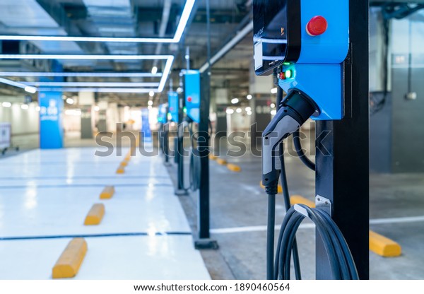 Electric car charging station for charge EV\
battery. Plug for vehicle with electric engine. EV charger. Clean\
energy. Charging point at car parking lot. Green power. Future\
transport technology.