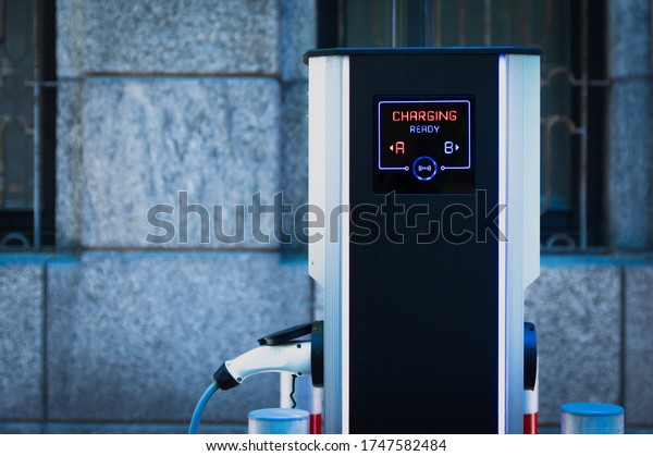 Electric car charging station in city parking with\
active Charging sign in\
red