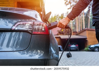 Electric car charging with station, EV fuel advance and modern eco system, Save the earth conception. man connecting a charging cable to a car from an electric car charging station. - Shutterstock ID 2059575932