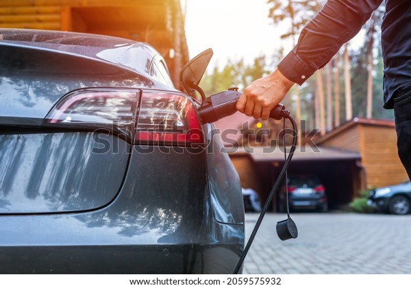 Electric car\
charging with station, EV fuel advance and modern eco system, Save\
the earth conception. man connecting a charging cable to a car from\
an electric car charging\
station.