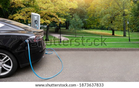 Electric car with a charging station on a background of city park