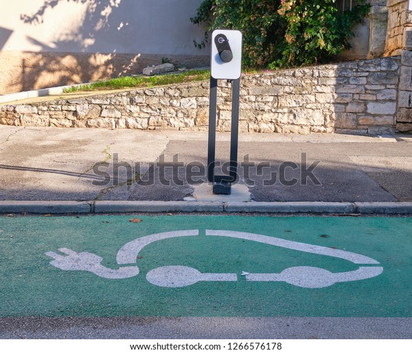 Electric\
car charging station on the side of street, with logo on the\
ground.  Renewal energy and environment\
concepts