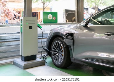 An Electric Car Is Charging At A Charging Station In The Parking Lot 