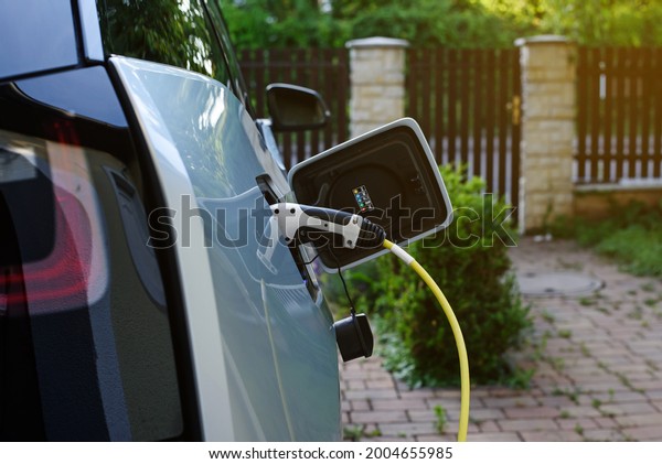 Electric car charging station. Power\
supply joined to modern electric car being\
charged.
