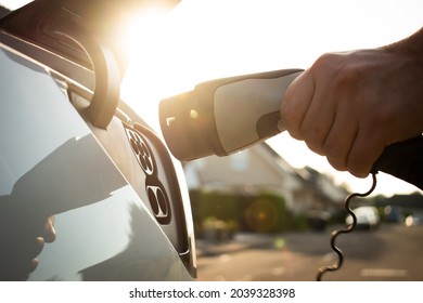 Electric car charging with sun in the background - Shutterstock ID 2039328398