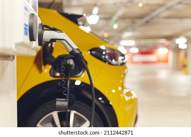 Electric car charging in underground car park in shopping center - Shutterstock ID 2112442871