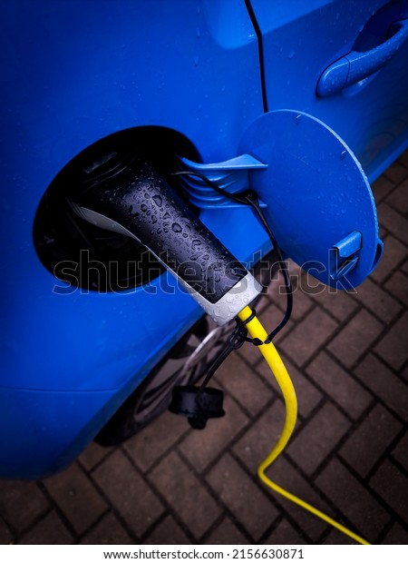 Electric car close-up at charging station.\
Transportation charging with ev charger in water drops, top view.\
Concept of green energy and eco\
power.