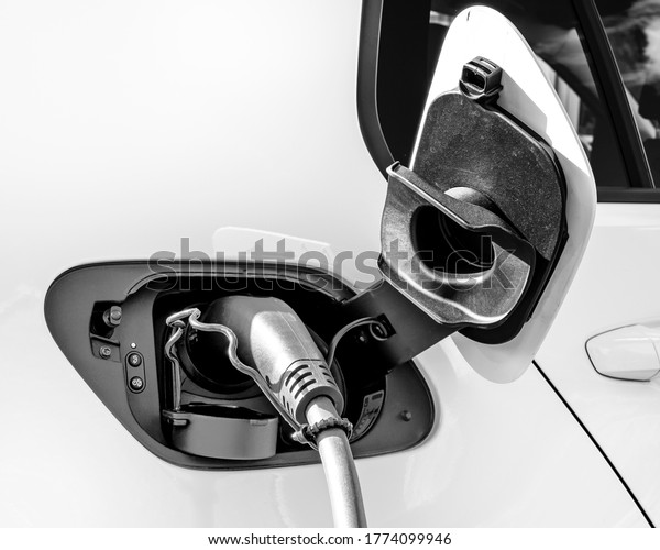 Electric car connected to a charging point with its\
charging lead in place
