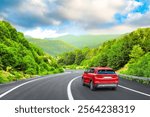 Electric car drive on spring road in beautiful nature landscape. spring colors in green mountain road landscape. summer view on highway in forest. nature trip in summer. Red suv car drive on highway.