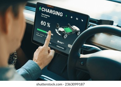 Electric car driver checks battery charging status, range and charging limit on app screen in the car. Smart technology device show EV car recharging data of electric storage in car battery innards. - Powered by Shutterstock