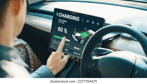 Electric car driver checks battery charging status, range and charging limit on app screen in the car. Smart technology device show EV car recharging data of electric storage in car battery innards.