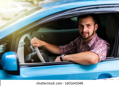 Electric car driver - green energy biofuel concept. Male behind wheel. Man driving new ecofriendly vehicle in nature forest. Young male owner proud confident looking at camera, Taxi driver concept.