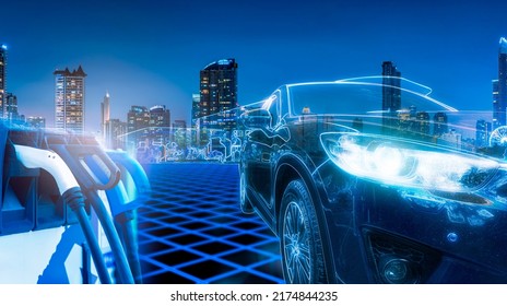 Electric Car And EV Car Charging Station At Gas Station With Cityscape Background In Futuristic Vehicle Concept. Electric Vehicle In Smart City At Night. Sustainable Power. Clean And Green Energy.