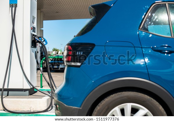 Electric car on gas station.\
Blue car and electric plug for charging. Ecology green fuels\
concept.