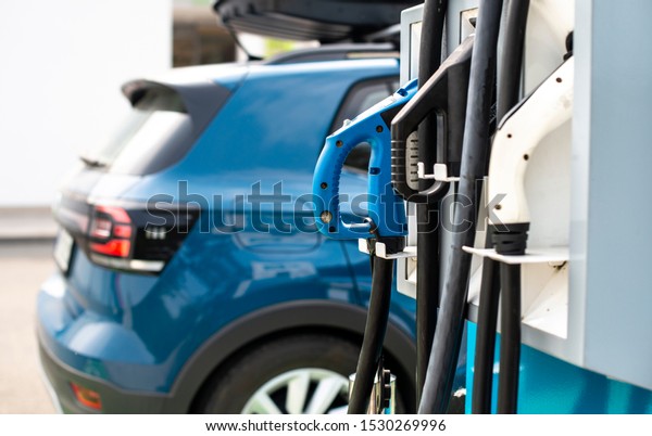 Electric car on gas station.\
Blue car and electric plug for charging. Ecology green fuels\
concept.