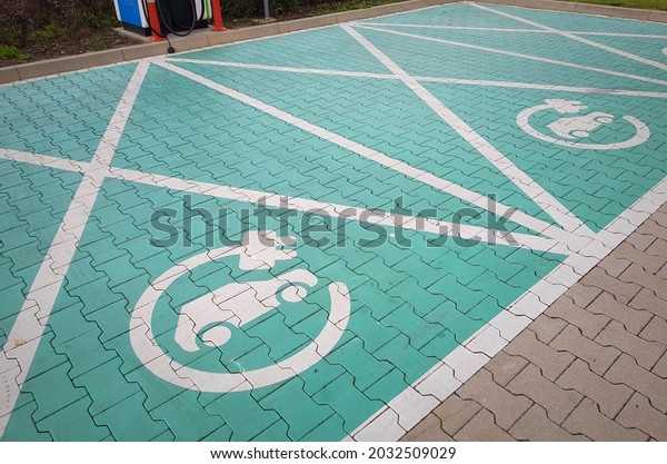 Electric car parking spot with charger. Green parking\
spot, electric car sign. Green paving stones. Car charging concept.\
  