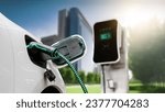 Electric car plug in with charging station to recharge battery with electricity by EV charger cable in eco green city park. Future innovative EV car using alternative clean energy reducing CO2. Peruse