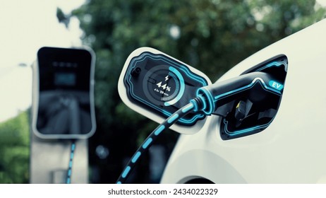 Electric car plug into EV charger cable from charging station display smart digital battery status hologram in eco green park and foliage background. Energy sustainability technological advance.Peruse - Powered by Shutterstock