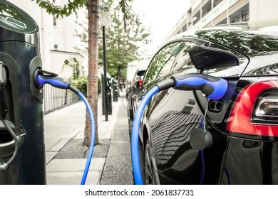 Electric car plugged in and changing on urban city street