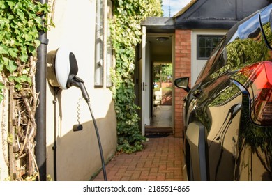 Electric car plugged in to charge outside home with power cable
