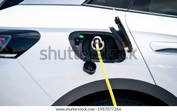 Electric car power cable plugged\
into car charging station booth futuristic modern technology\
loading electricity energy, power supply battery charge energy\
electro mobility eco\
environment-friendly
