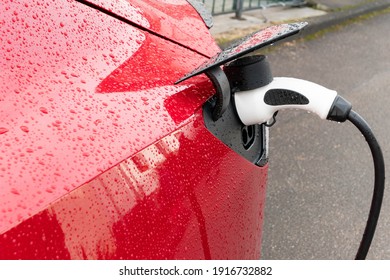 Electric car with raindrop in red is charged with plug - Powered by Shutterstock