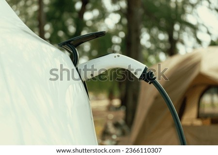 Electric car recharging battery at outdoor EV charging station at natural vacation campsite, alternative and sustainable energy technology eco-friendly car with holiday and travel concept. Perpetual Foto d'archivio © 