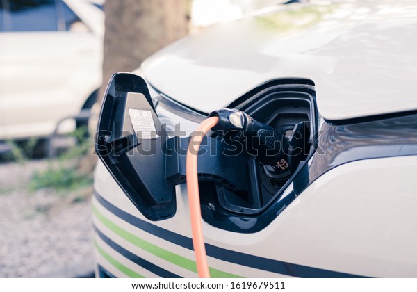 Electric car recharging with charge cable and plug\
leading to charge point.\
