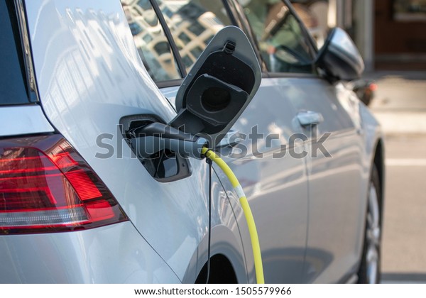 Electric Car\
silver color - plugged in for charging. charging station for\
electric car. Close up of the power supply plugged into an electric\
car being charged. Car charging\
cable.