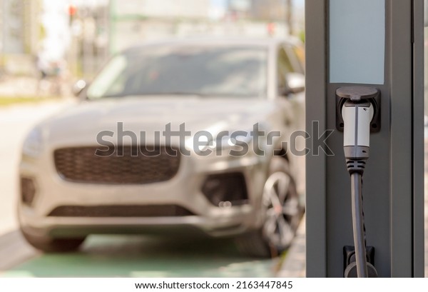 Electric car at\
Сharging station. E-charging slot on vehicle background. EV Car\
with the power cable supply\
plugged.