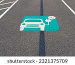 An electric charging sign on the asphalt road under the sunlight
