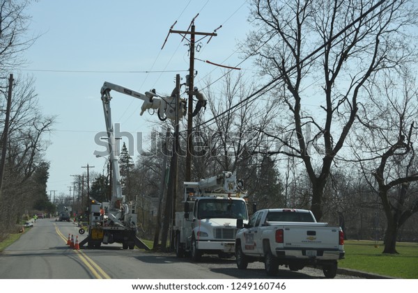 Electric Company vehicles and Utility workers in\
a cherry picker working on an electrical problem beside a utility\
pole, Bluffton, OH, April 12,\
2018