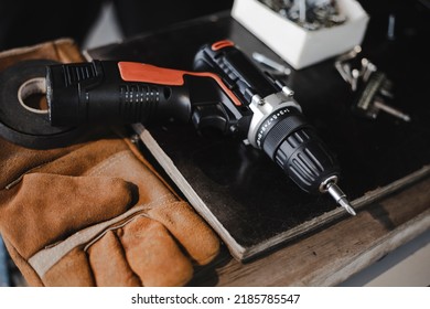 Electric cordless screwdriver on the table. Tapping screws made of steel on white wood background, metal screw, iron screw, chrome screw, screws as a background, wood screw, concept industry. 
