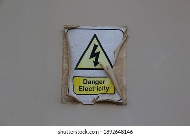 Electric Danger Symbol With A Words DANGER ELECTRICITY. Sticker Is Old And Peeled Off And Burnt-out 