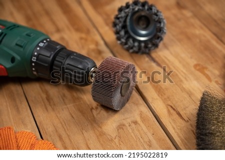 Electric drill, flap wheel, knot bowl wire disk, metal brush against the wooden background. Electric and hand tools for woodworking. Indoors. Selective focus.