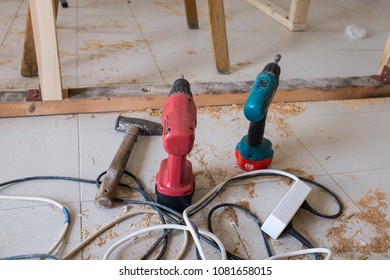 Electric drills on the floor in a carpentry workshop, a hammer lots of cables and sawdust lying around