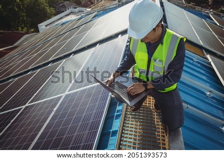Electric engineer working white safety on height building, installing solar panels on the rooftop working using notebook computer, inspecting, measuring, collecting data for repairing