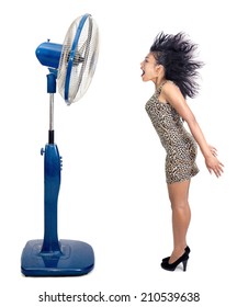 Electric Fan Blowing Wind At A Screaming Woman With Flying Hair. A Woman Stands Near A Big Fan Isolated On White Background. Woman Blowing The Hair From The Air Flow From The Fan.