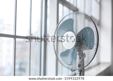 Electric fan near window in room