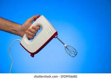 Electric Food Mixer Held In Hand By Caucasian Male Hand Studio Shot Isolated On Blue Background.