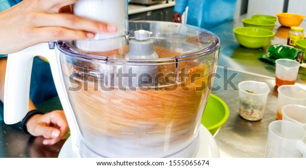 Electric food processor in fast spinning
action while mixing a variety of ingredients together. The process
renders the mixing bowl sample contents
blurry.